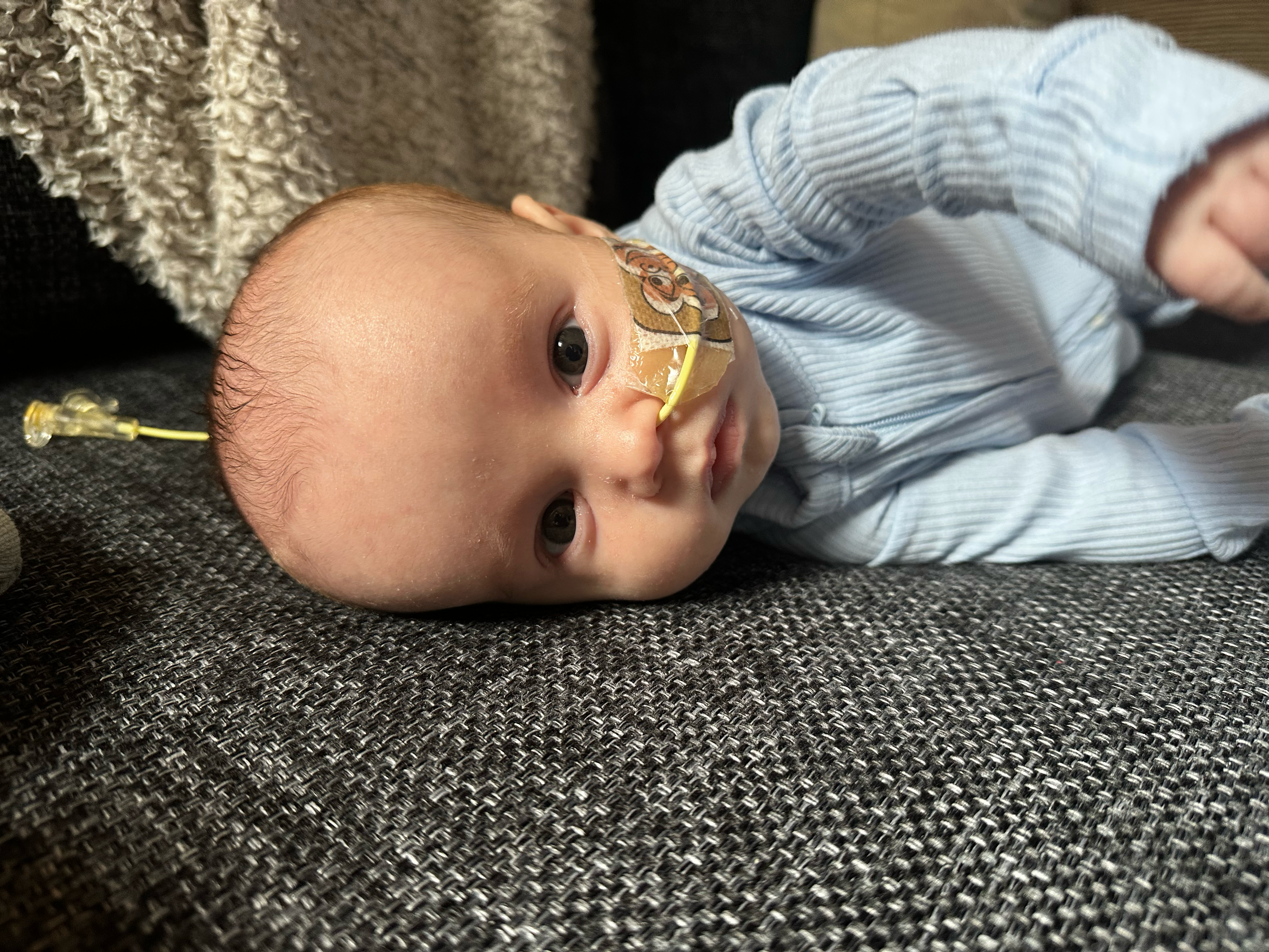 Nate lying on a couch in a blue sleeper and looking toward the camera