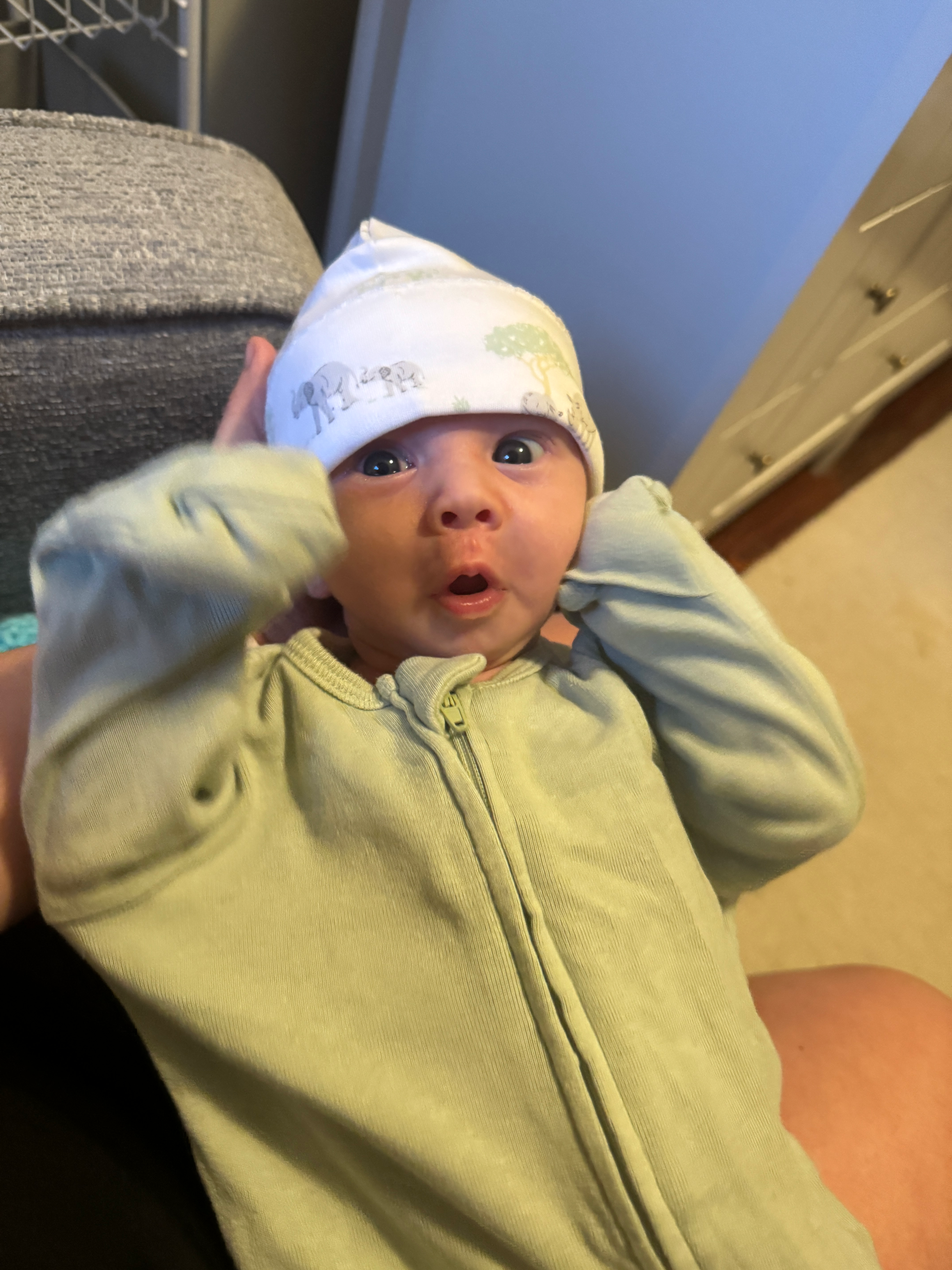 Nate in a pale green sleeper and hat, wide-eyed and cozy